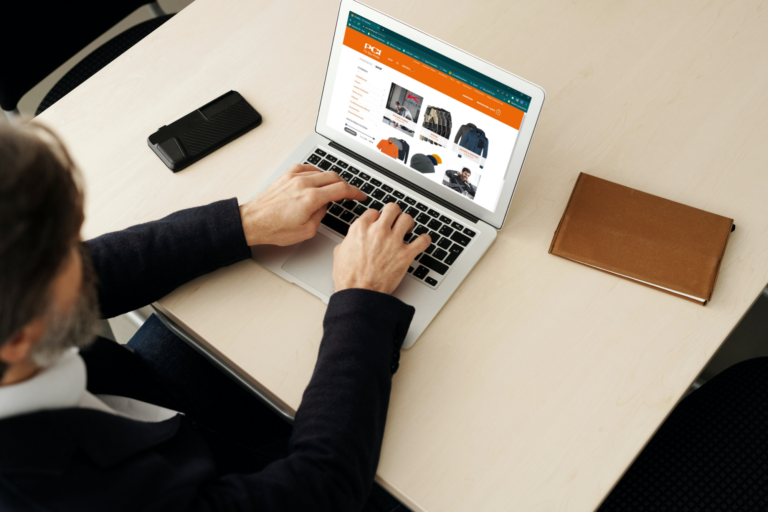 Mitarbeiter tippt auf Laptop im firmeneigenen Antholzer-Webshop für Arbeitskleidung